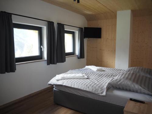 a bedroom with a bed and two windows at Zwiesler Haus Bschlabs in Bschlabs