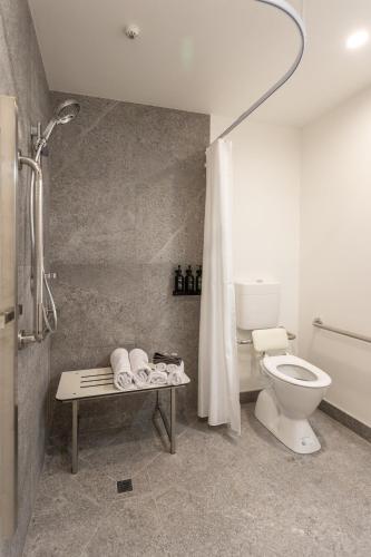 a bathroom with a toilet and a shower and a table at Arluxia in Auckland