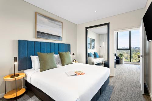 a bedroom with a large bed with a blue headboard at Quest Woolooware Bay in Woolooware