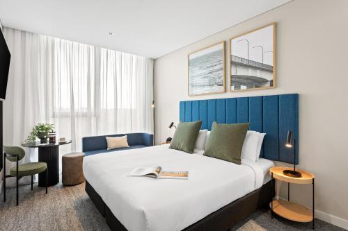 ein Hotelzimmer mit einem großen Bett mit blauem Kopfteil in der Unterkunft Quest Woolooware Bay in Woolooware