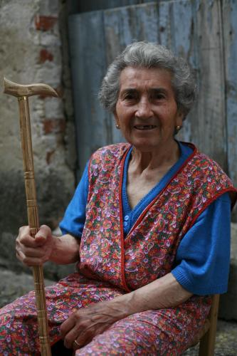 an older woman sitting in a chair holding a guitar at La Magara in Civita