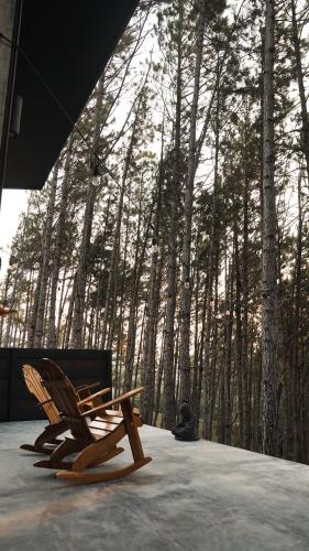 two wooden chairs sitting in front of a forest at Cozy Hideaway in the Mountains of Altos de María in Lagartero