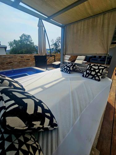 a bed with pillows and a canopy with a swimming pool at Casa Aguila Gran Reserva in Ixtapan de la Sal