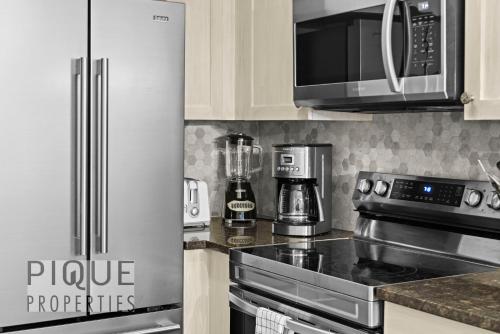 a kitchen with a stainless steel refrigerator and a microwave at Mystic Mountain Chalet, Heated Outdoor Pool & Hot Tub, Free Parking, Fast Wifi! in Canmore
