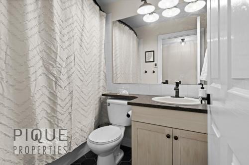 a bathroom with a toilet and a sink and a mirror at Mystic Mountain Chalet, Heated Outdoor Pool & Hot Tub, Free Parking, Fast Wifi! in Canmore