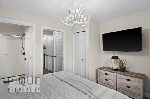 a bedroom with a bed and a flat screen tv at Mystic Mountain Chalet, Heated Outdoor Pool & Hot Tub, Free Parking, Fast Wifi! in Canmore
