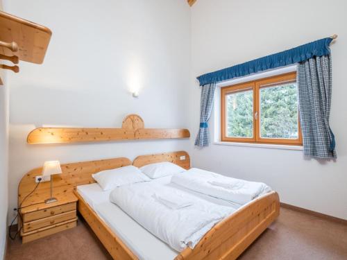 1 dormitorio con cama de madera y ventana en Reiterblick Ski in - Ski Out en Saalbach Hinterglemm