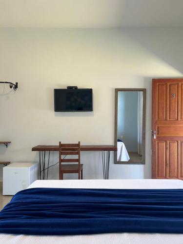 a bedroom with a bed and a table and a mirror at Pousada Recanto Rainha do Lago in Capitólio