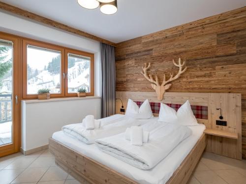 Schlafzimmer mit einem großen weißen Bett und Holzwänden in der Unterkunft Arianne Ski in - Ski out in Saalbach-Hinterglemm
