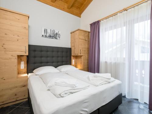 a large bed in a room with a large window at Traumlage Ski in - Ski out in Saalbach Hinterglemm