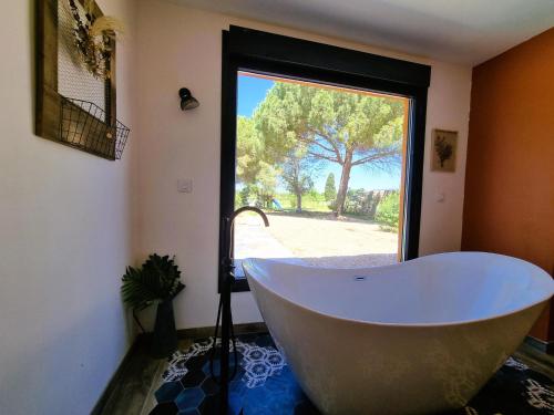 eine Badewanne im Bad mit einem großen Fenster in der Unterkunft Le Catamaran in Sallèles-dʼAude