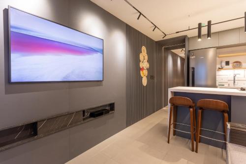 a tv hanging on a wall with two bar stools at Loft com jacuzzi privativa frente mar do Bessa in João Pessoa