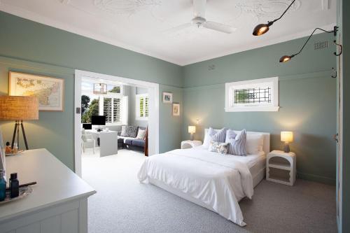 a bedroom with a white bed with blue walls at Modern Muse, Bellevue Hill in Sydney