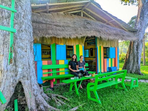 two people sitting in front of a colorful house in a tree at 4 Pohon - Les 4 Arbres in Pandang