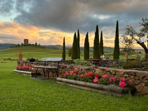 Dimora Buonriposo Pienza Country House في Contignano: حديقة بحائط حجري وطاولة وزهور