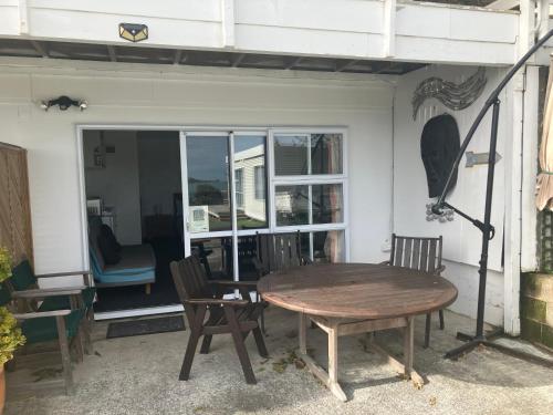 a patio with a wooden table and chairs and a window at Omapere Beach Apartments in Opononi