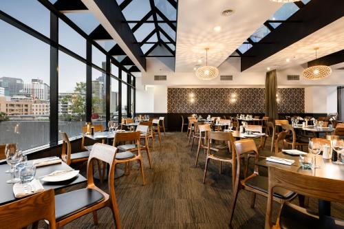 a restaurant with tables and chairs and windows at Hotel Grand Chancellor Brisbane in Brisbane