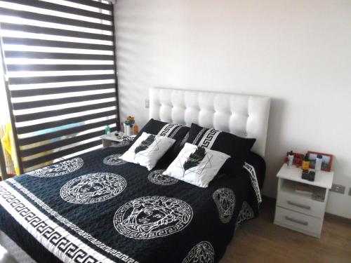 1 dormitorio con cama blanca y negra con almohadas en hermoso departamento con vista al mar, en Antofagasta