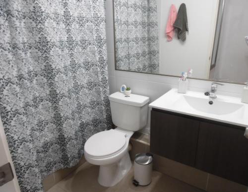 W łazience znajduje się toaleta, umywalka i lustro. w obiekcie hermoso departamento con vista al mar w mieście Antofagasta