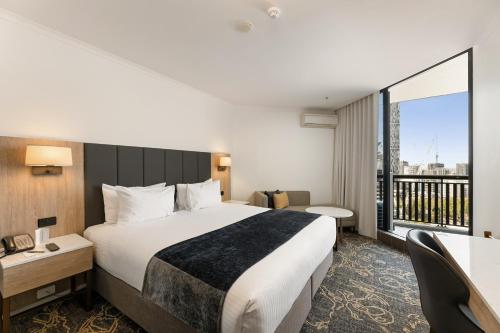 a hotel room with a bed and a large window at Hotel Grand Chancellor Brisbane in Brisbane