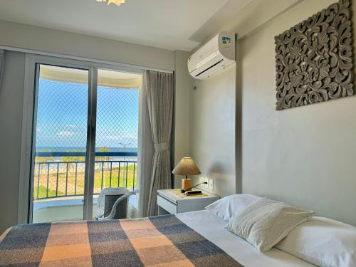 a bedroom with a bed and a view of the ocean at AllMar Flats - Apartamentos frente mar - Beach Village in Fortaleza