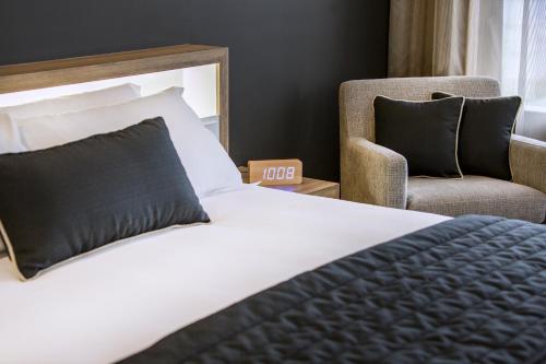 a hotel room with a bed and a chair at Hotel Grand Chancellor Brisbane in Brisbane