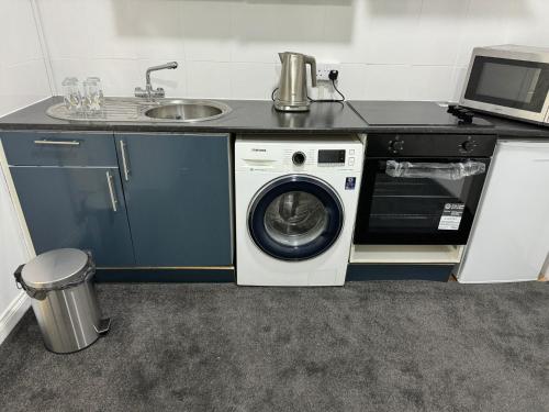 a kitchen with a washing machine and a sink at Flat in Cheam in Sutton
