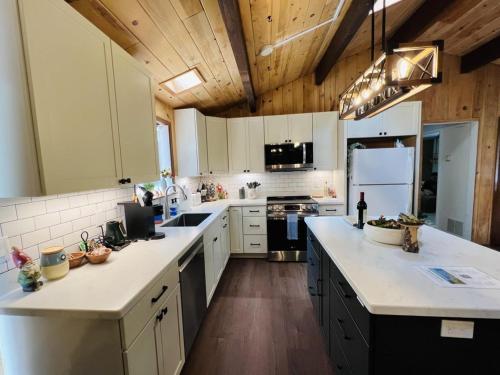 a large kitchen with white cabinets and wooden ceilings at Perch - Ellie's Secret Cabin in Coupeville