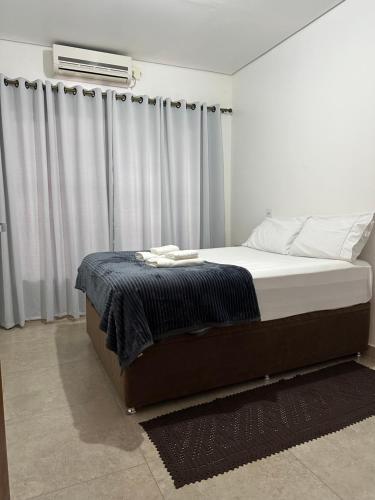 um quarto com uma cama com um cobertor e cortinas em Casa em Condominio próximo trevo Cataratas em Cascavel em Cascavel