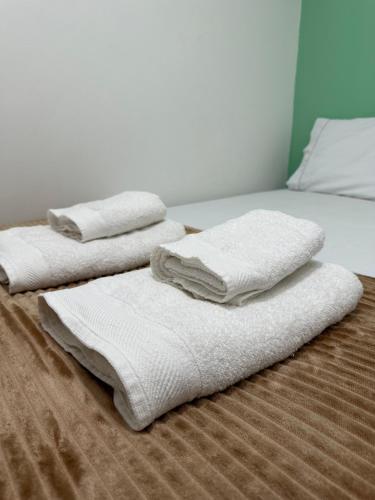 three white towels sitting on top of a bed at Casa em Condominio próximo trevo Cataratas em Cascavel in Cascavel