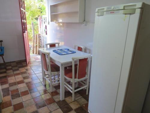 eine Küche mit einem Tisch und Stühlen sowie einem Kühlschrank in der Unterkunft Suites Delicia in Passa Quatro
