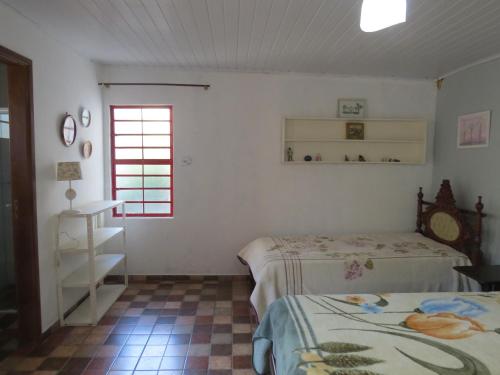 1 Schlafzimmer mit 2 Betten und einem Fenster in der Unterkunft Suites Delicia in Passa Quatro