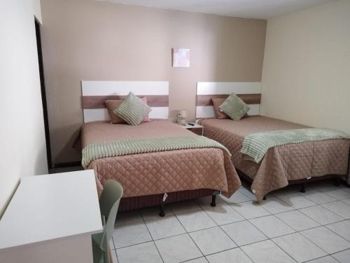グアテマラシティにあるUrban Homeのベッド2台とテーブルが備わるホテルルームです。