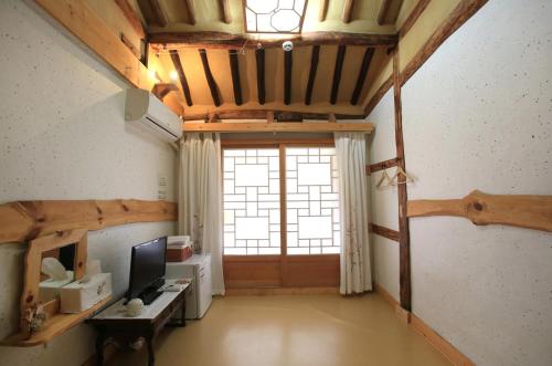 an attic room with a large window and a television at Hanok Madang in Jeonju