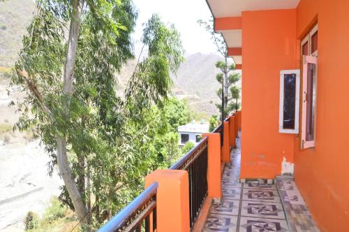 a balcony of a house with orange walls and trees at GAYATRI HOMESTAY in Rudraprayāg