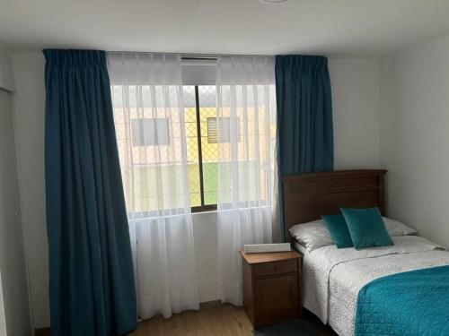 a bedroom with a bed and a window with blue curtains at Espectacular casa para la Exponor in Antofagasta
