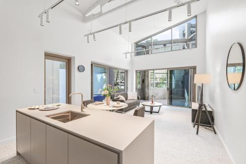 a kitchen and living room with white walls and windows at Stanley Lane Residence Darlinghurst in Sydney