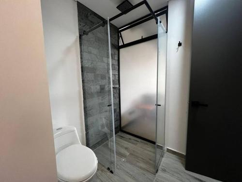 a bathroom with a toilet and a glass shower stall at Cercano al Aeropuerto y nuevo in Pereira