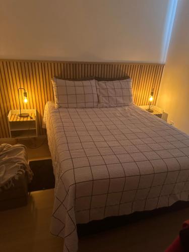 a bedroom with a large bed with two lamps at Apê da Sil in Sao Paulo