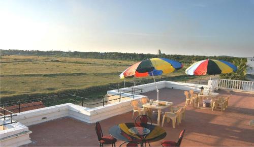 two umbrellas and tables and chairs on a patio at The Palmyrah Tenements in Mysore