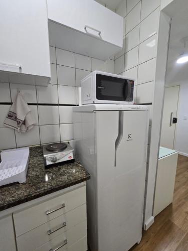 a microwave on top of a refrigerator in a kitchen at Apartamento aconchegante in Brasília