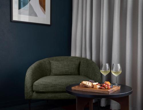 a table with a chair and two glasses of wine at Rydges Auckland in Auckland