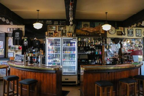 a bar with a refrigerator and some bar stools at Formerly the Blackball Hilton in Blackball