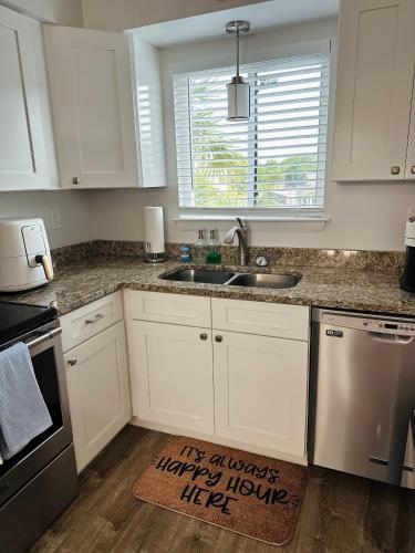 a kitchen with white cabinets and a sink and a window at Condo at Happy Hour Tybee in Tybee Island