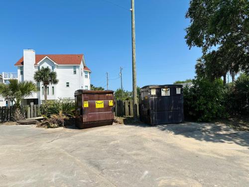 two garbage containers are sitting in front of a house at Condo at Happy Hour Tybee in Tybee Island