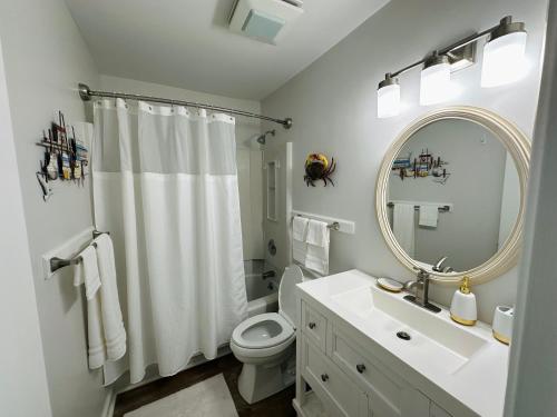 a bathroom with a sink and a toilet and a mirror at Condo at Happy Hour Tybee in Tybee Island