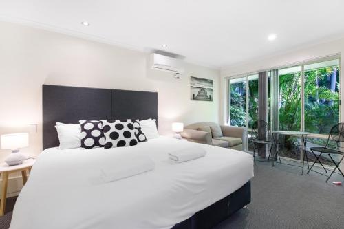 a bedroom with a large white bed and a living room at Oceanique in Coffs Harbour