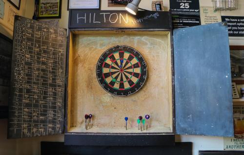 un tablero de dardos en una pared con tres personas en él en Formerly the Blackball Hilton en Blackball