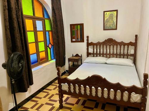 um quarto com uma cama de madeira e um vitral. em Casa Grande Hostal em Medellín