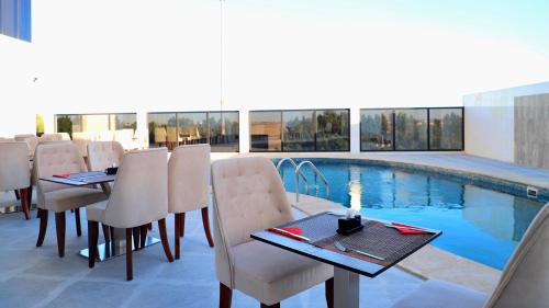 a restaurant with a table and chairs and a pool at Five Seasons Hotel in Tabuk